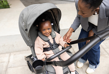 Un jeune enfant confortablement installé dans sa poussette Joie